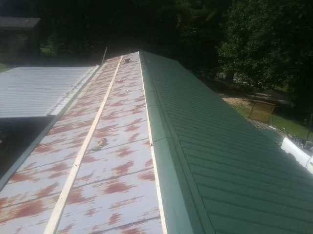 Old rusted panels beside newly installed green metal roofing — Wind Damage Roof Repair by Roofing Brothers in Chesterville