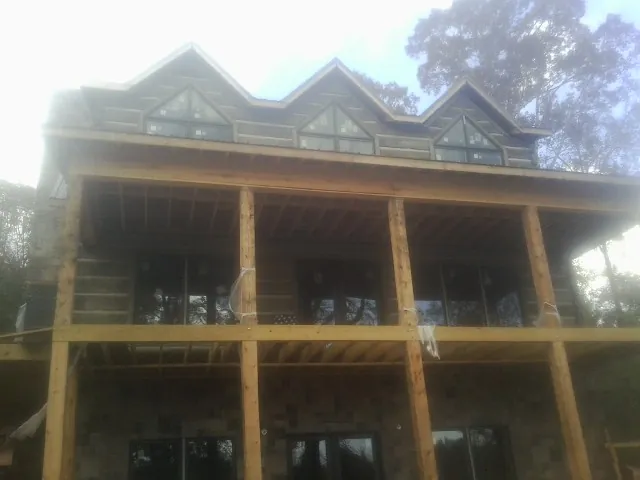 Dormers and porch framing on a large log home under construction — Roof Coating work by our crew in Chesterville