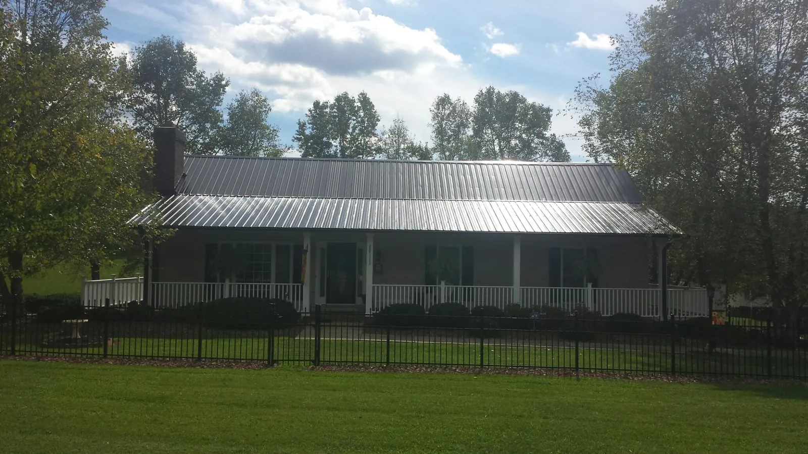 Gray metal roof on a brick ranch with a full width front porch — Gutter Guard Installation work by our crew in Chesterville