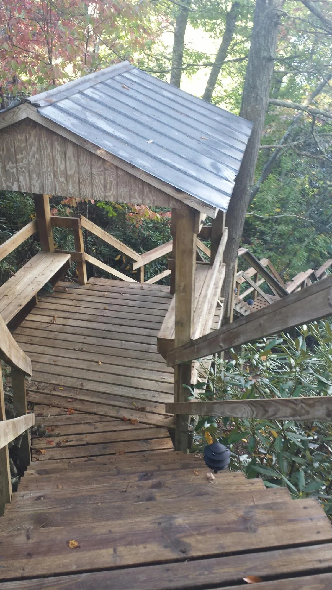 Metal roofed shelter over wooden steps on a wooded walkway — Skylight Repair & Installation work by our crew in Chesterville