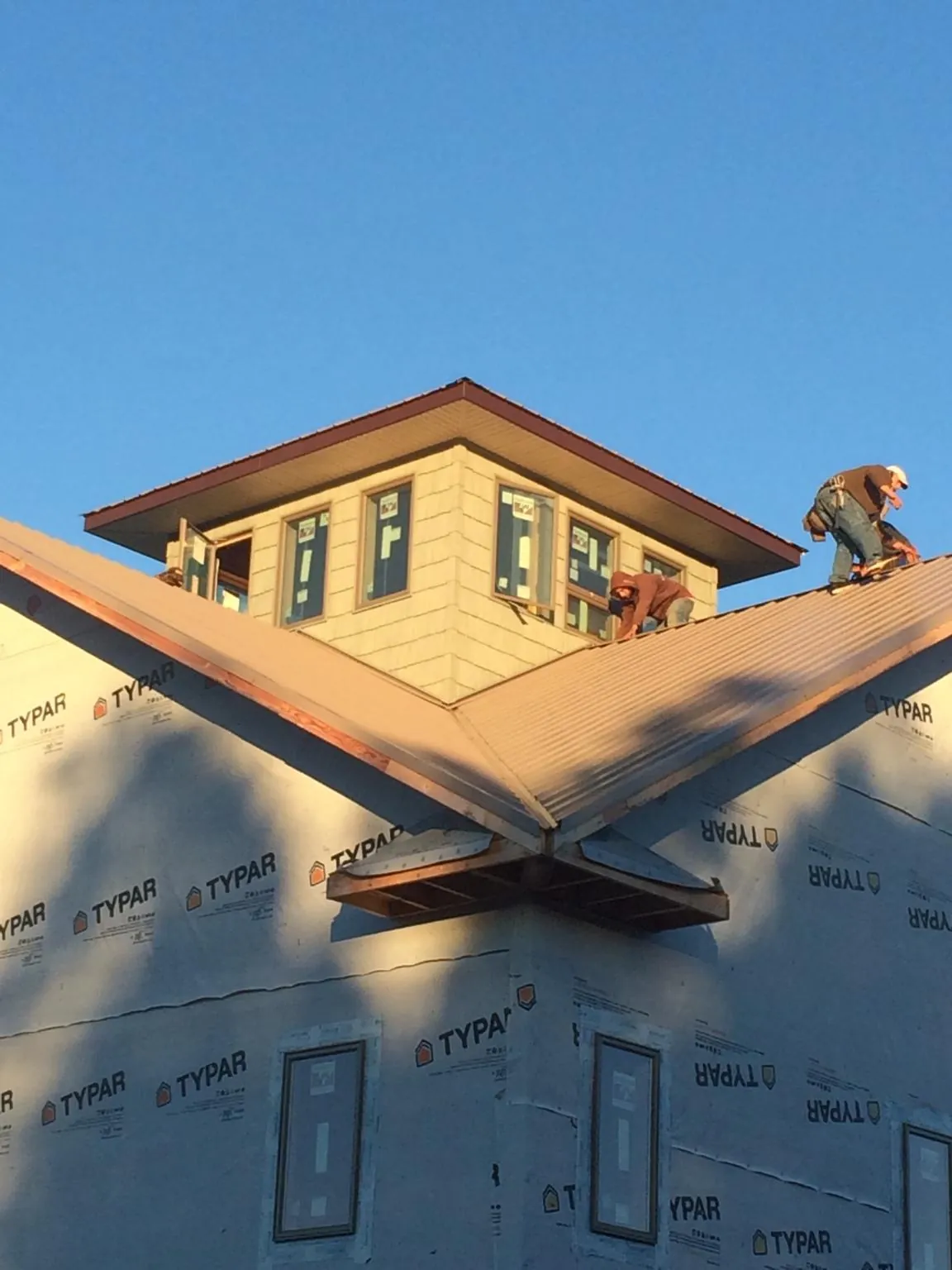 Roofers working around a rooftop cupola on a new metal roof at sunset — Roof Waterproofing in Chesterville by Roofing Brothers